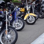 Image of parked motorcycles with helmets on the handlebars.