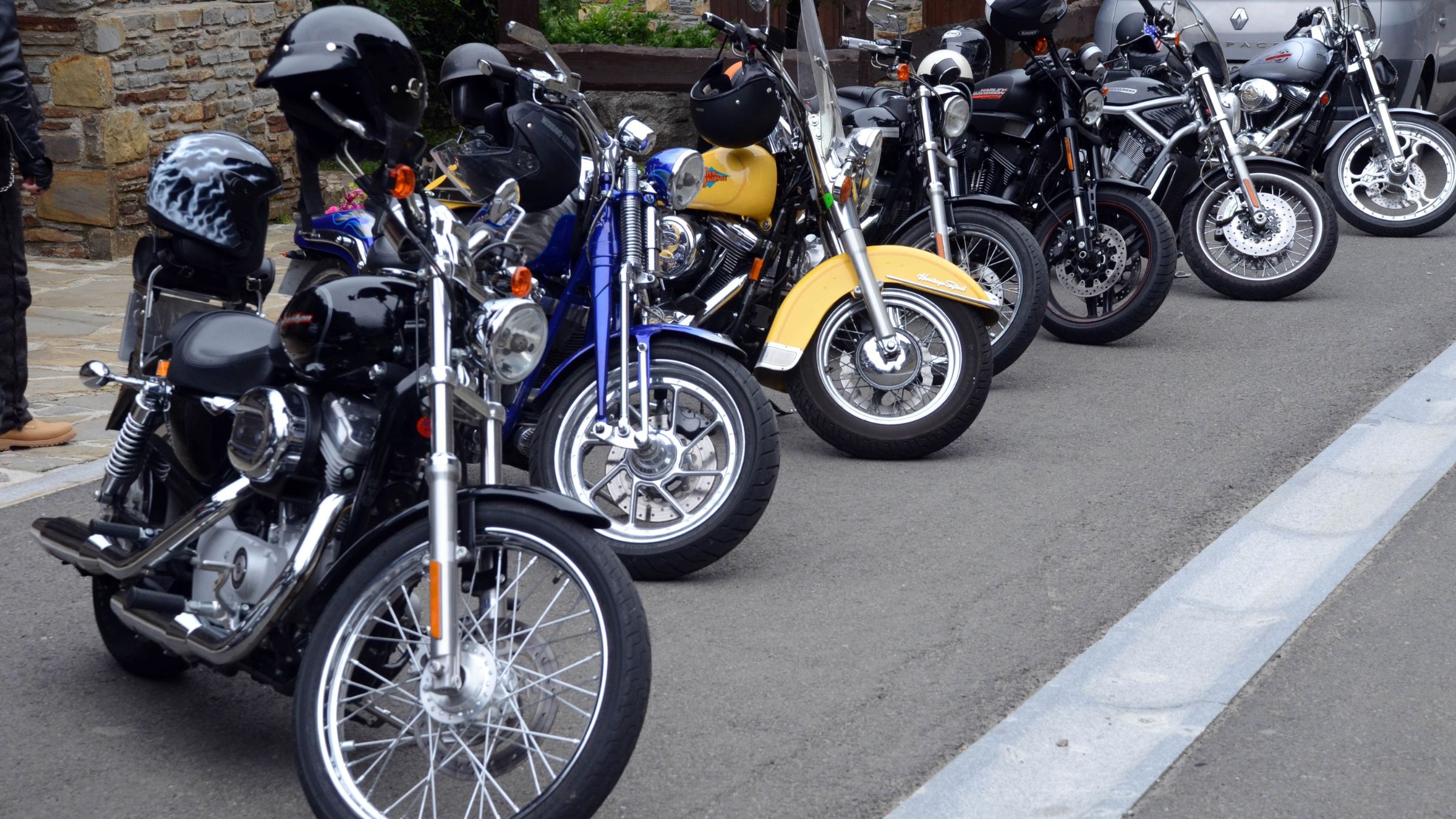 Image of parked motorcycles with helmets on the handlebars.