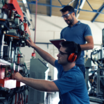 Two people in a warehouse performing some manufacturing processes.