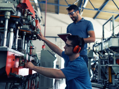 Two people in a warehouse performing some manufacturing processes.